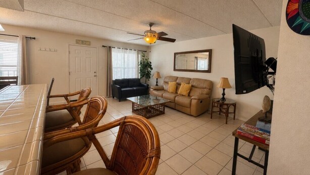 A living room with a dining table, chairs, a sofa, a coffee table, a television, and a ceiling fan. - Two Bedroom One Bath Off The Beach (South Padre Island)