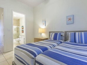 Een slaapkamer met twee bedden, een nachtkastje, een lamp en een zeester decoratie aan de muur.