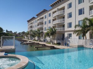 Ein Hotel mit Schwimmbad, mehreren Balkonen und Palmen.