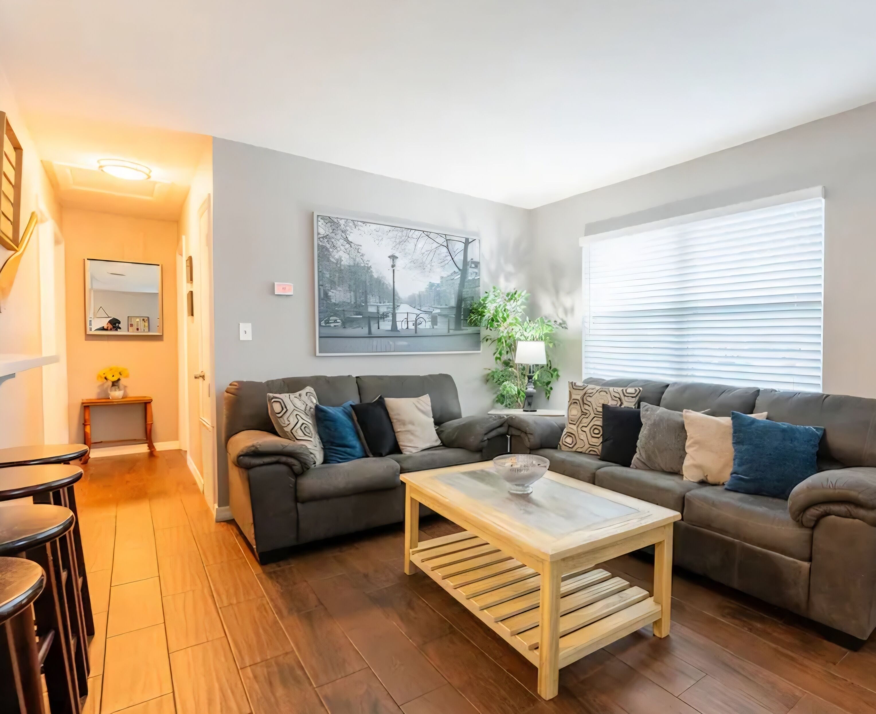 A living room with a grey sofa, a wooden coffee table, and a mirror on the wall.