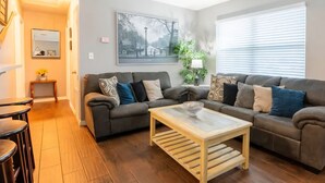 A living room with a grey sofa, a wooden coffee table, and a mirror on the wall. - Welcoming home with everything you need in Cocoa - 2 bedrooms (Cocoa)