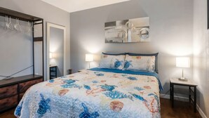 A bedroom with a bed, two bedside lamps, a wall-mounted artwork, and a wooden dresser. - Welcoming home with everything you need in Cocoa - 2 bedrooms (Cocoa)