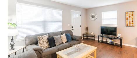 A living room with a sofa, coffee table, TV, and a clock on the wall.