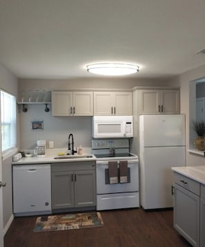 A full kitchen with white cabinets, a microwave, a refrigerator, and a dishwasher.