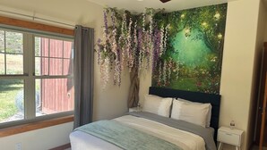 Ein Schlafzimmer mit Bett, Nachttisch, Fenster und Deckenventilator.