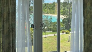 A view from a room with a sliding glass door to a pool and beach. - Beach Condo (St. John's)