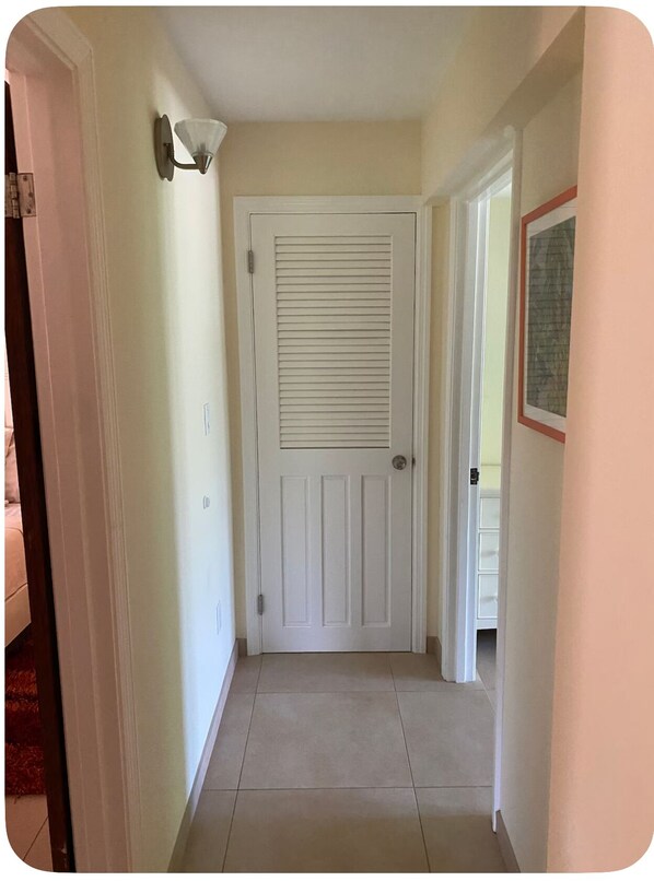 A hallway with a white door, a light fixture, and a framed picture on the wall.
