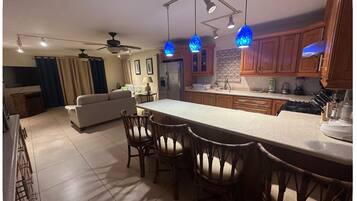 A modern kitchen with a central island, wooden cabinets, and pendant lighting.