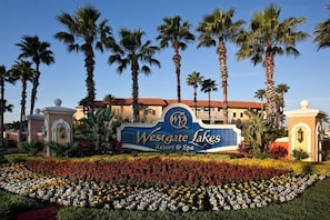 Segnaletica del Westgate Lakes Resort & Spa, con palme e un giardino fiorito.