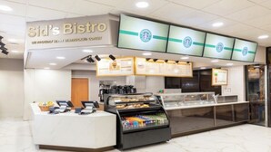 Una cafetería Starbucks con mostrador, carteles de menú y una vitrina con pastelería.
