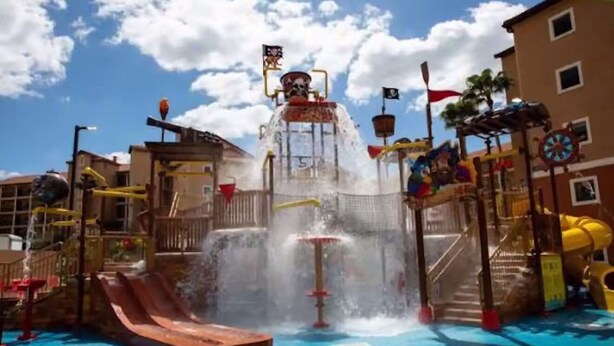 Un parque acuático con toboganes, una fuente de agua y una estructura con temática pirata.