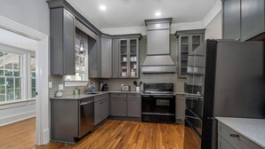 A modern kitchen with grey cabinetry, a black refrigerator, and a wooden floor.