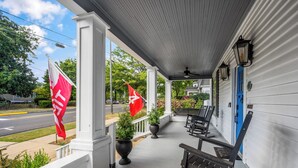 A porch with white columns, a blue door, and two flags.