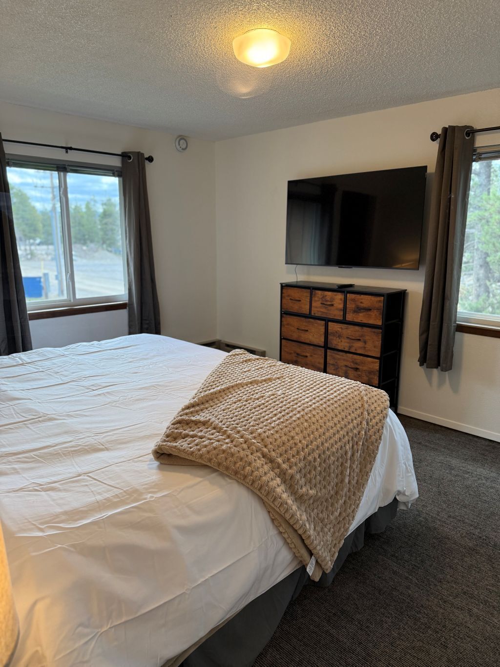 Ein Schlafzimmer mit einem Bett, einem Fernseher an der Wand und einer Kommode.