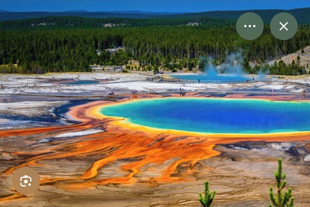 Ein geothermisches Gebiet mit einem großen, farbenprächtigen Wasserbecken, umgeben von Mineralablagerungen.