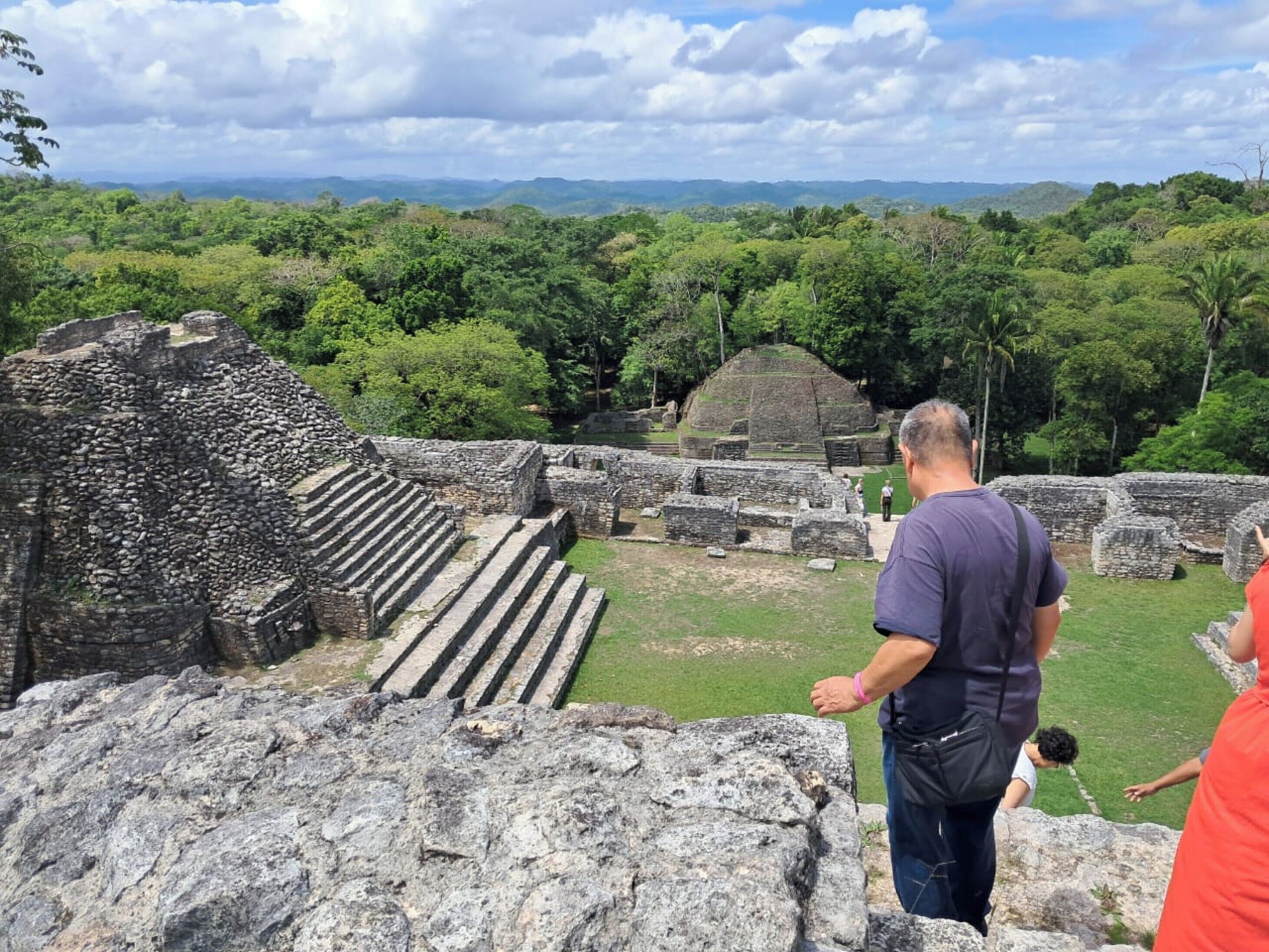 A historical site with ancient stone structures and a lush green landscape in the background.