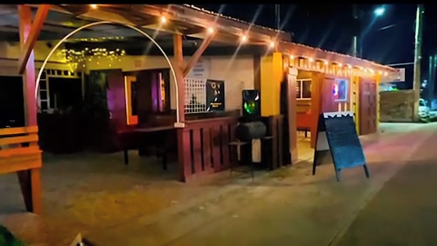 An outdoor seating area with tables and chairs, a counter, and a signboard. - MAXROOMZ (Santa Elena)