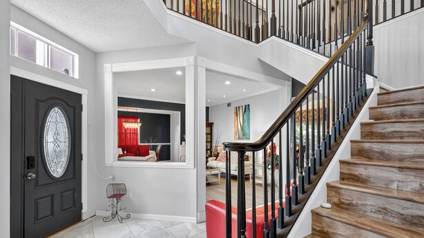 A modern interior with a staircase, a black door with a glass panel, and a red bench.