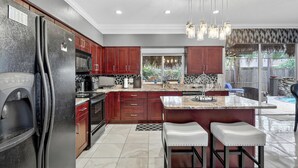A modern kitchen with a large island, stainless steel appliances, and a view of the backyard.