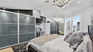 A modern bedroom with a large bed, a chandelier, and a wardrobe with frosted glass doors.