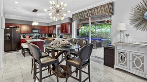 A modern kitchen with dark wooden cabinets, a central island, and a dining area with leather chairs.