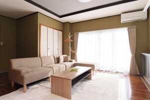 Una sala de estar con un sofá color beige, una mesa de centro de madera y un ventanal con cortinas.