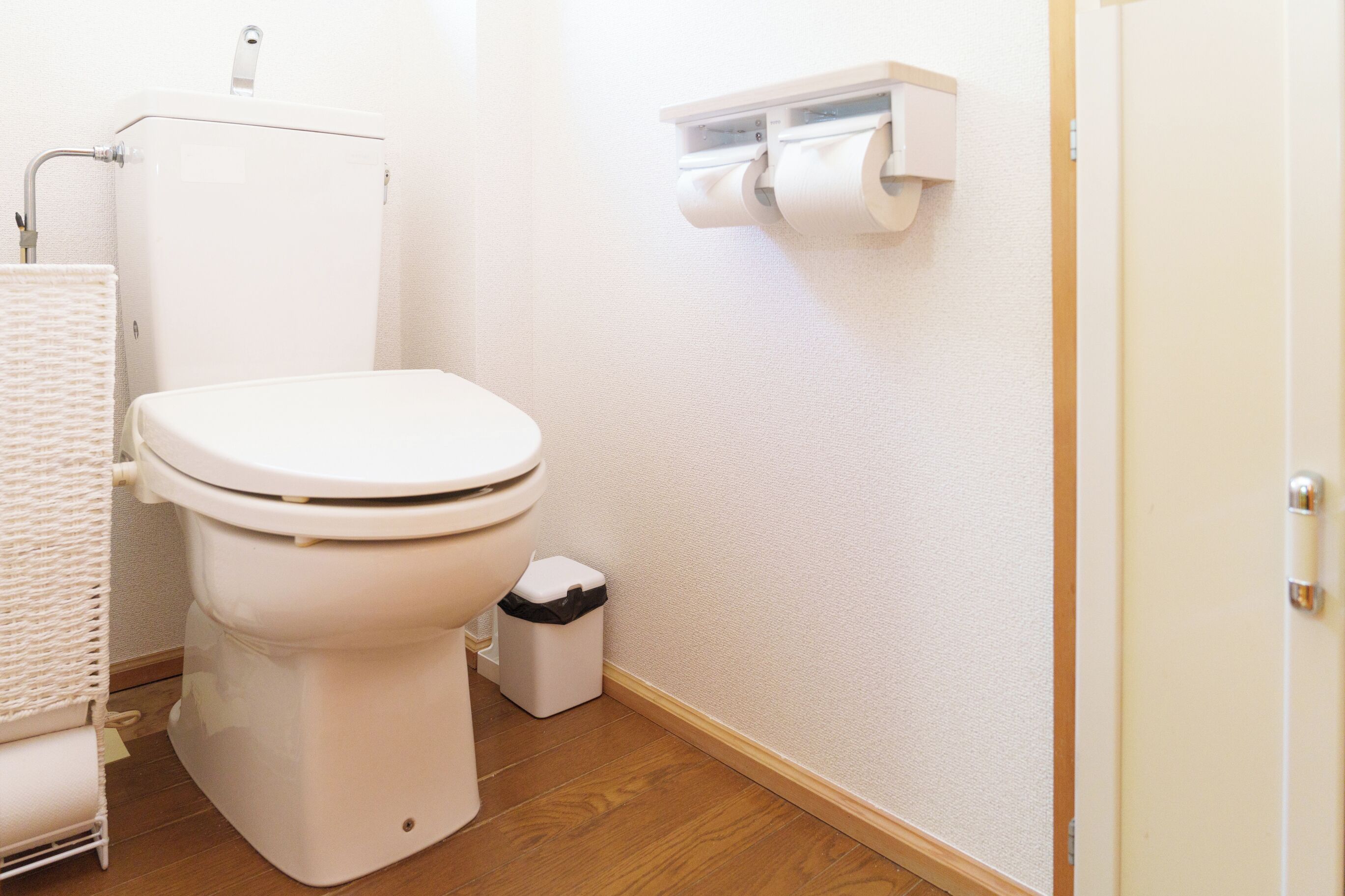 Une salle de bain équipée de toilettes, d’une poubelle et d’un porte-rouleau de papier toilette fixé au mur.