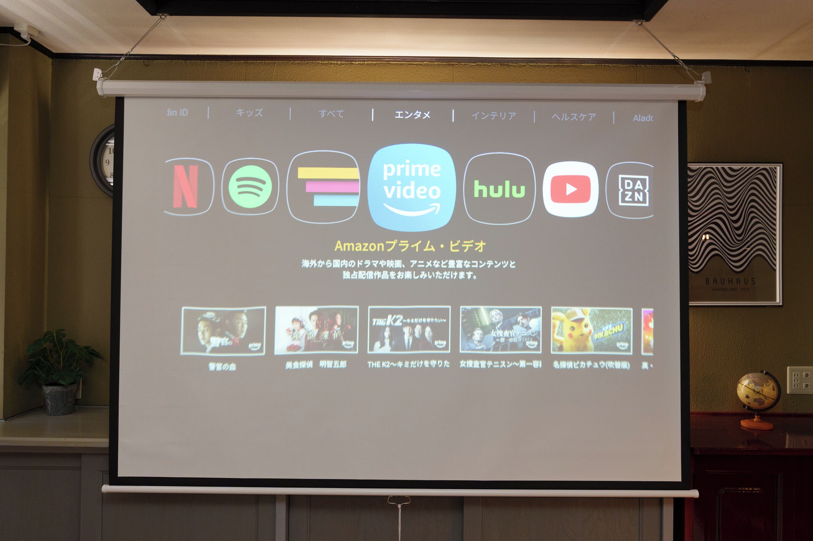 A presentation screen with logos of various streaming services and a projector screen displaying a menu.