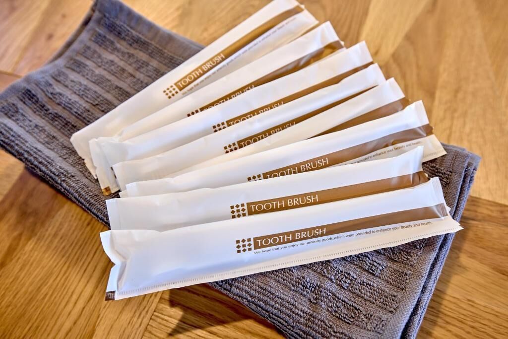A set of white toothbrushes with brown packaging labeled "TOOTH BRUSH" on a wooden surface.
