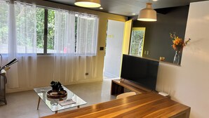 A modern living room with a wooden coffee table, a glass-top side table, a large mirror, and a TV on a wooden stand. - Great townhome with AC in Guácima, surrounded with nature and totally private (Guácima)