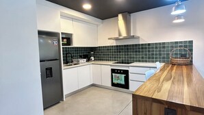 A modern kitchen with white cabinets, a stainless steel refrigerator, a built-in oven, and a wooden countertop. - Great townhome with AC in Guácima, surrounded with nature and totally private (Guácima)