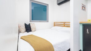 A neatly made bed with a white comforter and a mustard-colored throw blanket.