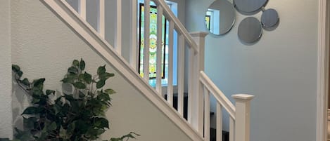 A staircase with white railings leading to a landing with a potted plant and a wall with circular mirrors.