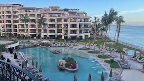 Un complex turístic amb una gran piscina, palmeres i vistes a l'oceà.