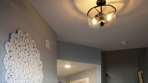 Un couloir avec une armoire blanche, un élément décoratif mural et un escalier.