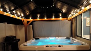Un bain à remous avec un plafond en bois et un barbecue sur une table.