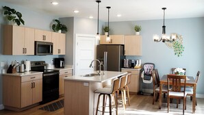 Une cuisine moderne avec des meubles en bois, des appareils en acier inoxydable et un îlot central doté de tabourets de bar.
