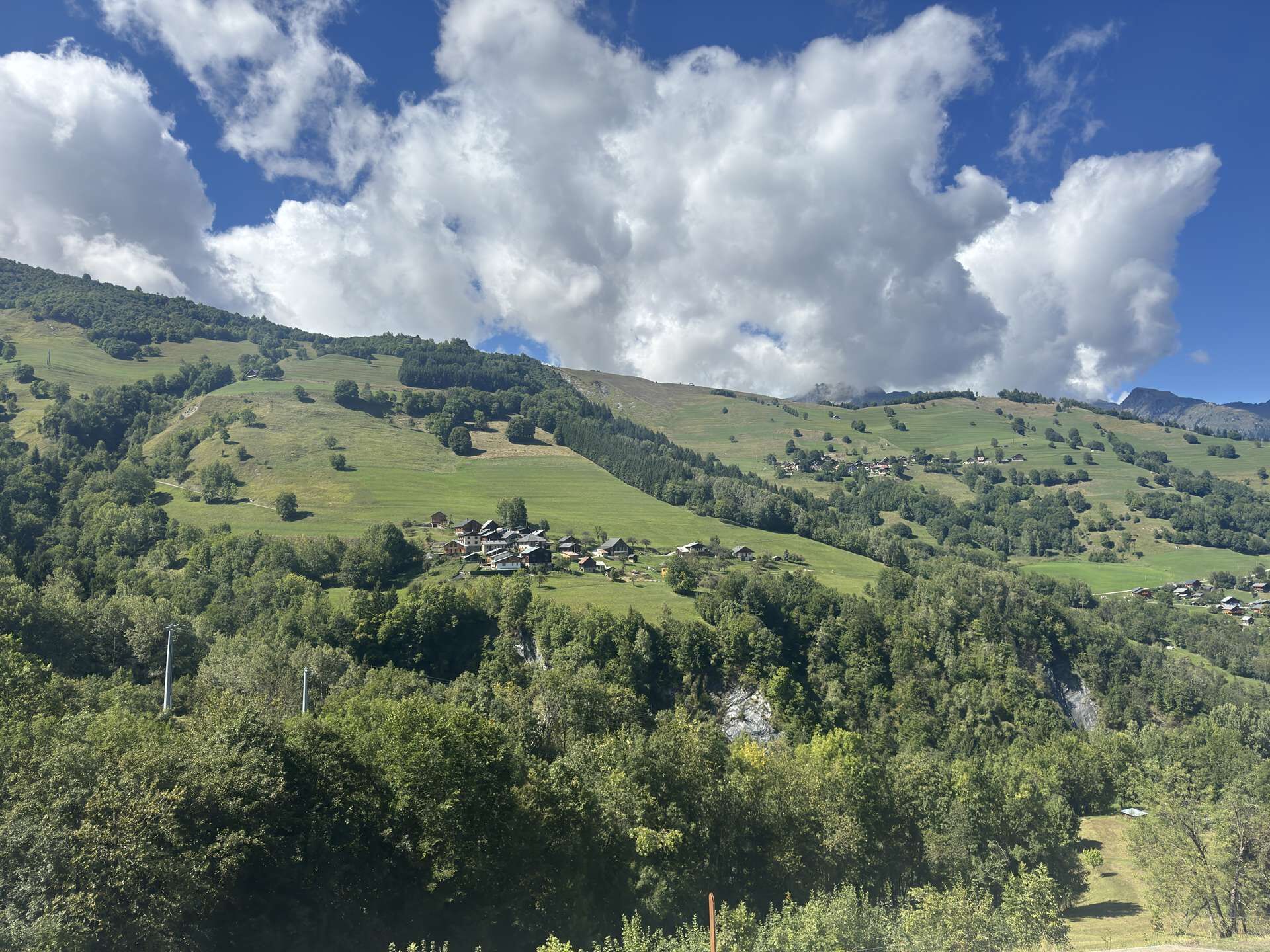 Ländliche Landschaft mit sanften Hügeln, verstreuten Häusern und ausgedehnten Waldgebieten.