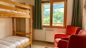A room with a bunk bed, a red chair, and a window with a view of greenery. - Le Roc - Magnificent, cosy 4-room apartment (LES AVANCHERS VALMOREL)
