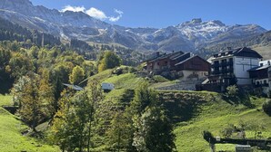 A mountain village with traditional wooden houses, a hotel, and a view of snow-capped peaks. - Le Roc - Magnificent, cosy 4-room apartment (LES AVANCHERS VALMOREL)