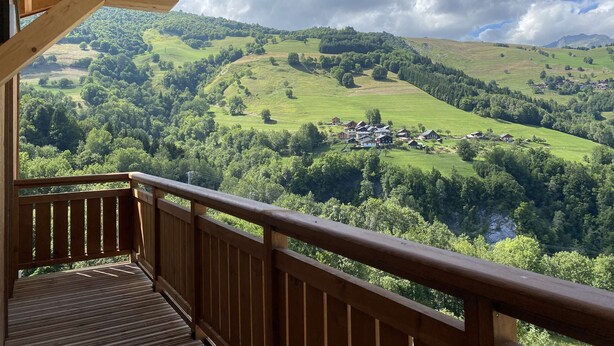 A wooden balcony with a view of a green valley and scattered houses. - Le Roc - Magnificent, cosy 4-room apartment (LES AVANCHERS VALMOREL)