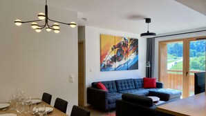 A modern living room with a dining area, a large painting, and a view through a sliding door. - Le Roc - Magnificent, cosy 4-room apartment (LES AVANCHERS VALMOREL)