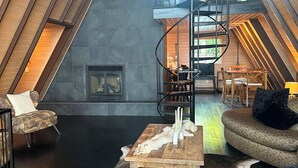 Un loft spacieux avec de hauts plafonds, un escalier en colimaçon, une cheminée et un coin salon confortable.