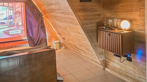 A room with a sloped ceiling, wooden paneling, a desk with a computer, and a wall with framed pictures.