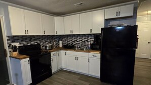 A kitchen with white cabinets, a black refrigerator, and a tiled backsplash. - “Waterfront Getaway on Wheeler Lake – Private Dock & Boat Ramp” (Hillsboro)