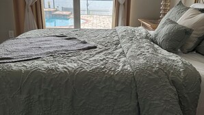 Un dormitorio con una cama grande, vista a una piscina y una lámpara en la mesita de noche.