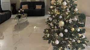 Una sala de estar con un árbol de Navidad, un ventilador de techo y una chimenea.