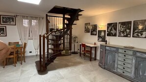Un espace repas comprenant un escalier en bois, une table à manger avec des chaises et un meuble avec des tiroirs.