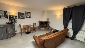 Un salon comprenant un canapé, une cheminée, une table à manger avec des chaises et un buffet.