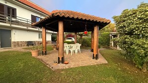 Un patio couvert, agrémenté d’une table et de chaises, entouré d’une pelouse bien entretenue et de plantes en pot.